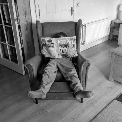 Thing two reclining in my new chair reading The Week Junior