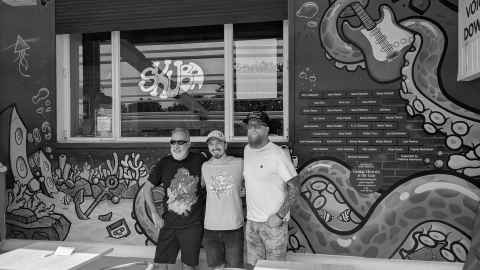 Unveiling of the guitar heroes at The Leas Cliff Hall wall, with two of the organisers and artist El Davo